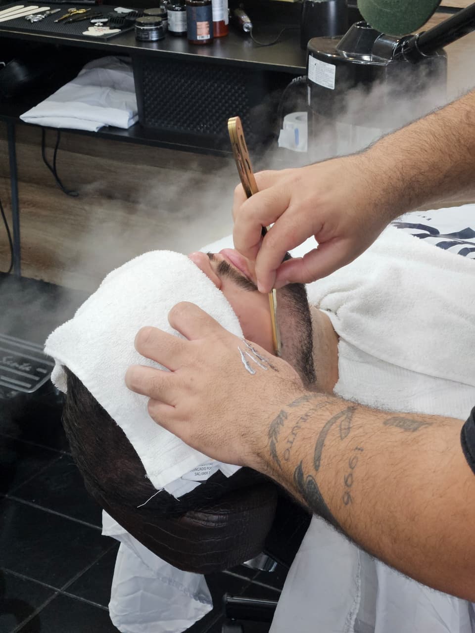 Barba sendo feita com navalha e toalha quente na Felps Barbearia